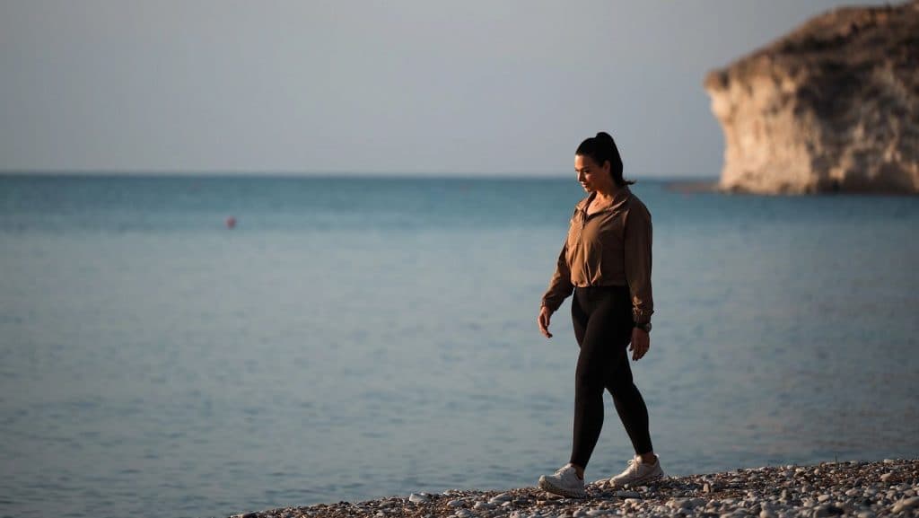 Individual walking along a coastal path, representing low-impact, repeatable cardio practice that supports long-term consistency.