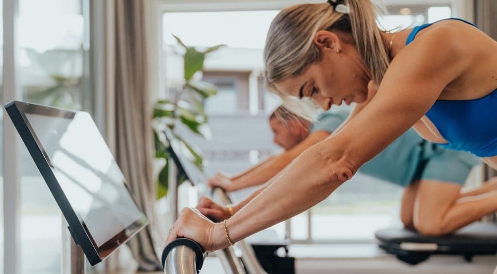Close-up of a participant practicing controlled reformer Pilates, emphasizing breath, focus, and intentional movement in a guided studio session.