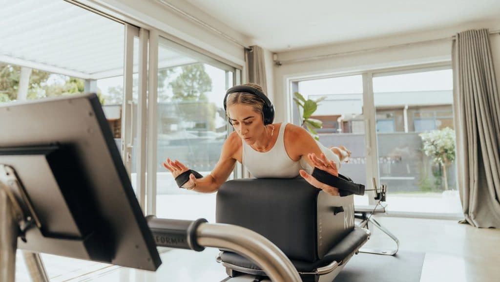 Individual performing controlled Pilates movements on a Reform RX-S reformer in a modern home setting.